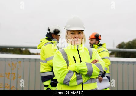 Engineers in reflective clothing standing on bridge Stock Photo