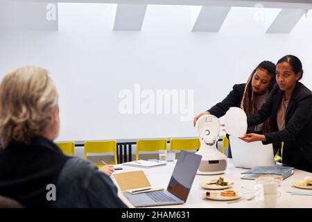 Business people discussing robot voice assistant during meeting Stock Photo