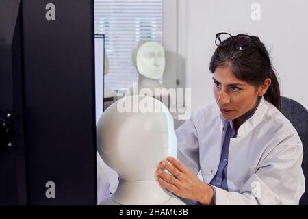 Female engineer building robot at work station Stock Photo