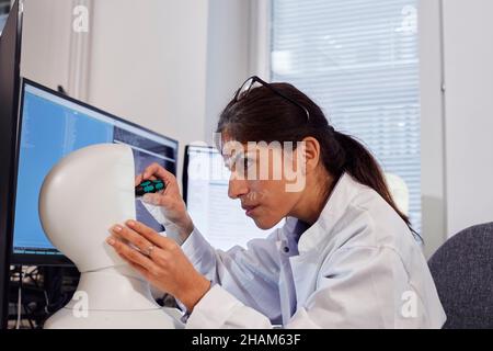 Female engineer building robot at work station Stock Photo