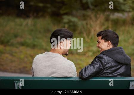 Rear view of men sitting on bench Stock Photo