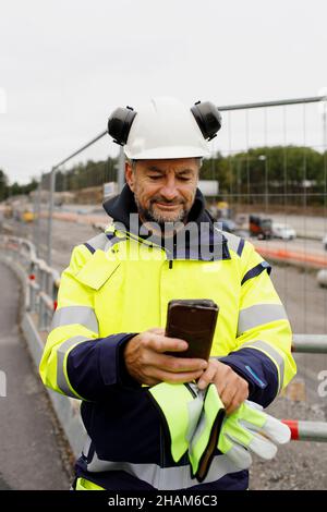 Male engineer in reflecting clothing using cell phone Stock Photo