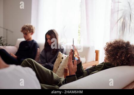 Siblings using smart phones in living room Stock Photo