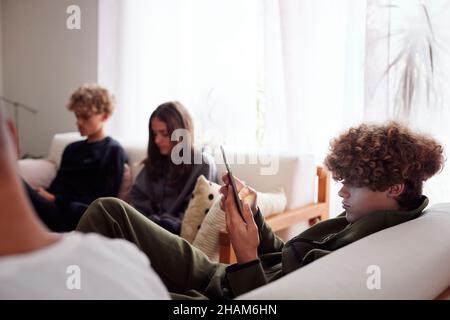 Siblings using smart phones in living room Stock Photo