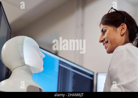 Smiling female engineer building robot Stock Photo