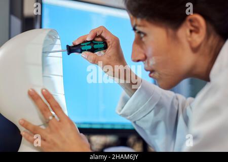 Female engineer building robot with screwdriver Stock Photo
