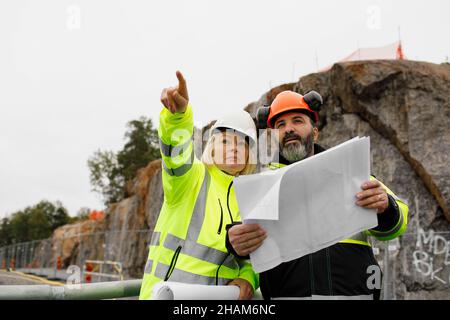 Engineers in reflecting clothing looking at blueprints Stock Photo