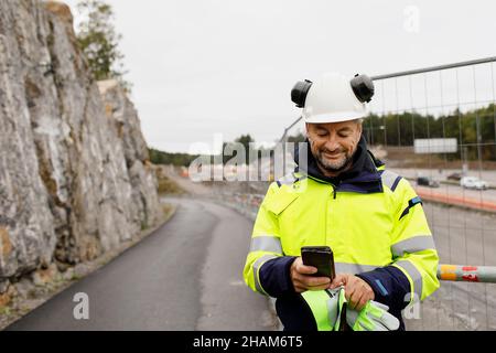 Male engineer in reflecting clothing using cell phone Stock Photo
