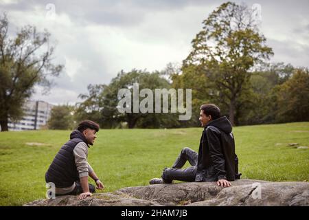 Smiling men sitting in park Stock Photo