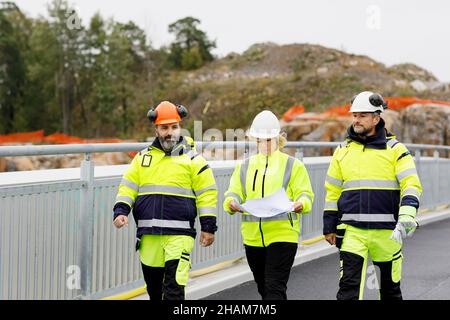 Engineers in reflective clothing walking on bridge Stock Photo