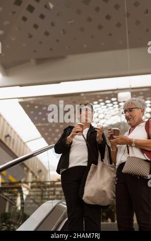 Smiling women on escalator Stock Photo
