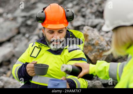 Engineers in reflective clothing having hot drink Stock Photo