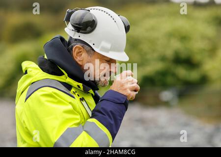 Male engineer in hard hat having drink Stock Photo