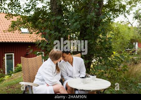 Young couple in bathrobes sitting at outdoor table Stock Photo