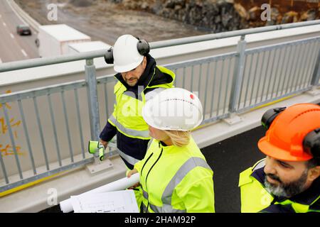 Engineers in reflective clothing walking on viaduct Stock Photo