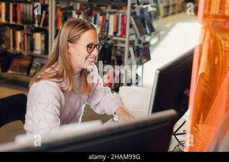 Woman using computer in library Stock Photo