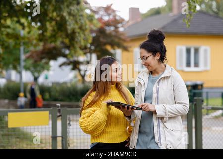 Smiling women using digital tablet outside Stock Photo