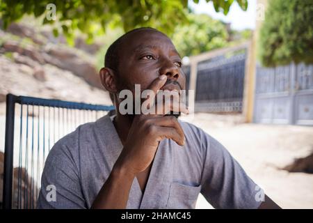 Close up portrait of thoughtful african male man sit and look analyzing outdoors Stock Photo