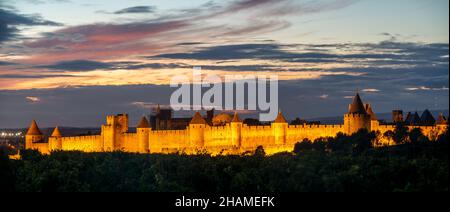 Lighted Carcassonne fortification walls seen from vineyards surrounding the city-Panorama. Stock Photo
