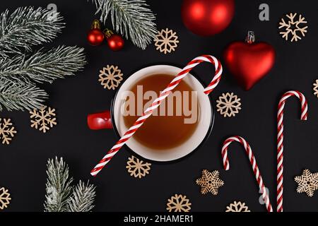 Cup of tea with Candy Cane and seasonal Christmas decoration on black background Stock Photo