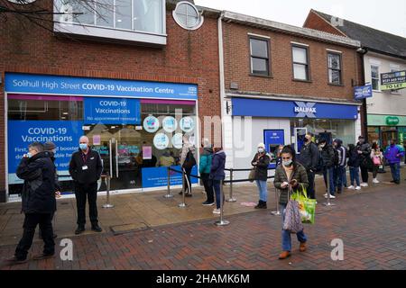 Hundreds of people queue at a vaccination centre on Solihull High Street, West Midlands, as the coronavirus booster vaccination programme is ramped up to an unprecedented pace of delivery, with every eligible adult in England being offered a top-up injection by the end of December. Picture date: Tuesday December 14, 2021. Stock Photo