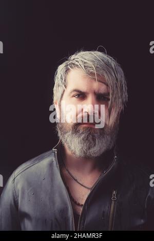 Portrait of brutal young man with long wet blond hair wearing leather jacket. Male fashion, beauty concept. Classic style. Studio shot. Stock Photo