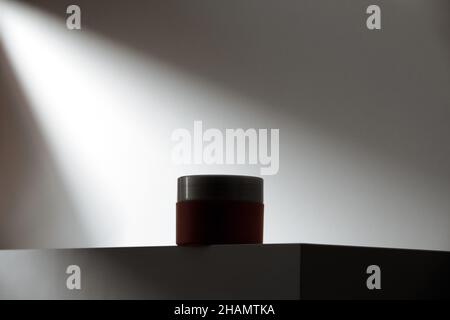 dark cream pot in ray of light on a podium. Low key moody advertisement. Surprise product dark horse. Hero shot Stock Photo