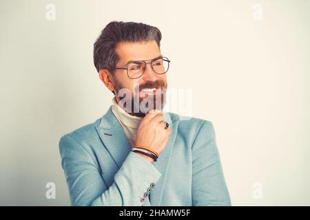 Young handsome man in blue suit and glasses smiling isolated on white. Stock Photo