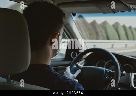 Young Adult Driving a Car with Dashboard Speedometer in Front of the Steering Wheel and Looking Forward Stock Photo