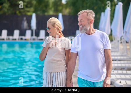 A man and a woman walking along the swimming pool Stock Photo