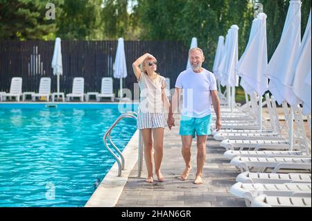 A man and a woman walking along the swimming pool Stock Photo