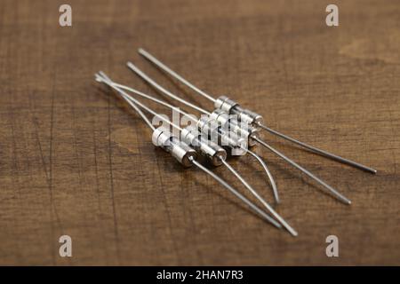 Electronic components: a few fuses on wooden table. Two-terminal passive components. Stock Photo