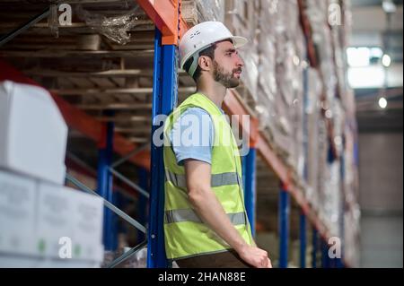 Profile of man in workwear leaning against metal counter Stock Photo