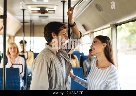 Cheerful young couple standing in bus and talking Stock Photo