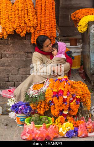 A vendor selling flower garlands holds her little girl in the early morning in Hanuman Dhoka Durbar Square, Kathmandu, Nepal. Stock Photo