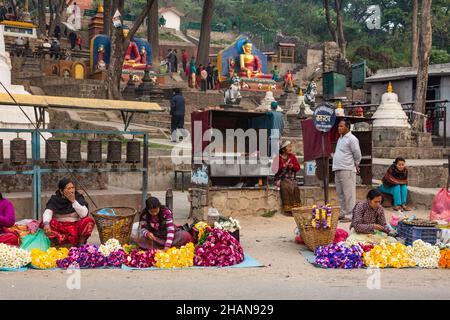 Vendors selling flower garlands for religious offerings at the entrance to the Swayambhunath temple complex, Kathmandu, Nepal. Stock Photo