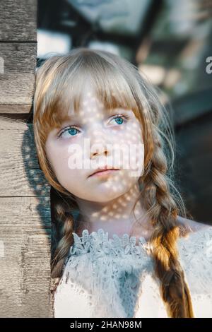 charming girl with long blonde hair. Chiaroscuro on the face, the play of sun glare. large portrait of an 11-year-old girl Stock Photo