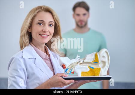 Smiling woman showing human ear model Stock Photo