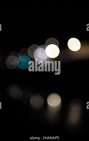 Out of focus colored lights on bridge with reflections in water Stock Photo