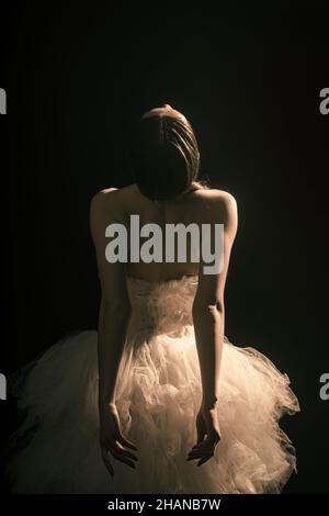 Young beautiful ballet dancer is posing in studio, view back. Stock Photo