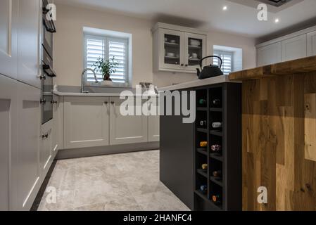 A light,contemporary, fitted kitchen with a wine rack,island,blinds (using mixed materials including blockwood).Has kitchen island with extractor fan. Stock Photo