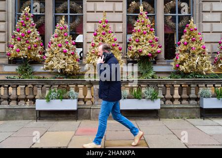 Edinburgh, Scotland, UK. 14th December  2021. General views of shops and bars in Edinburgh City Centre on day Scottish First minister made statement to Scottish Parliament about social restrictions to control current Omicron variant increase in Covid-19 cases in Scotland. Pic; Members of the public walk past bar decorated with Christmas trees. Iain Masterton/Alamy Live News. Stock Photo
