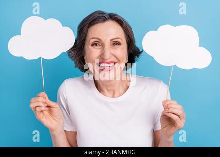 Portrait of attractive cheerful woman holding in hands two white clouds laughing good mood isolated over bright blue color background Stock Photo