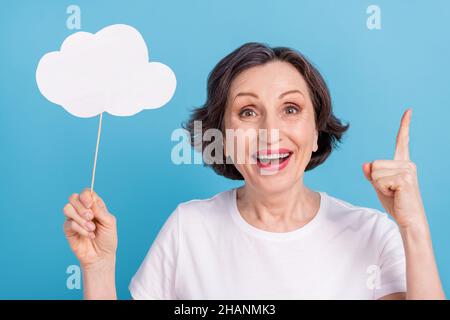 Portrait of attractive clever cheerful woman holding in hand white cloud pointing up isolated over bright blue color background Stock Photo