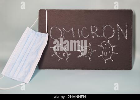 New Variant of the Covid-19 Omicron B.1.1.529 text. Face mask. Omicron variant of coronavirus. Chalk text on blackboard. Stock Photo