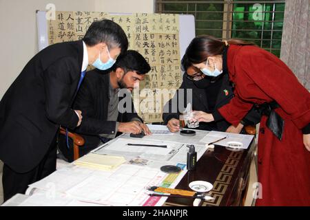 Lahore, Pakistan. 14th Dec, 2021. People learn Chinese calligraphy during an event held by the Confucius Institute at the University of the Punjab in Lahore, Pakistan, on Dec. 14, 2021. Credit: Jamil Ahmed/Xinhua/Alamy Live News Stock Photo