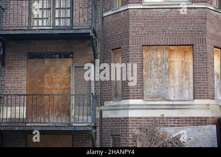 old abandoned apartment building with boarded up windows and rusty iron balconies Stock Photo