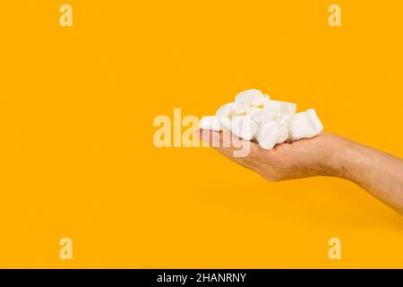Packaging foam chips on a man hand on a yellow background Stock Photo