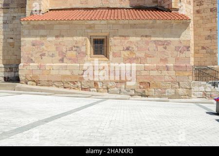 Old and small lattice window in the stone wall of a building in a town of Zamora, Spain, Europe. Wall of a church in summer. Stock Photo