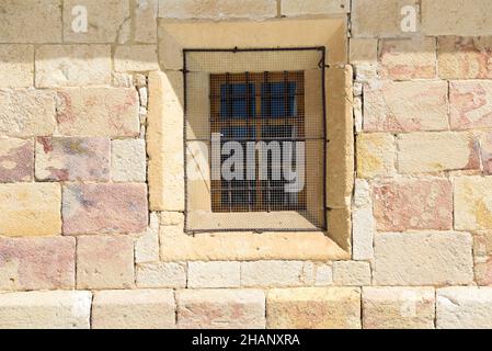 Old lattice window in the stone wall of a building in a town of Zamora, Spain, Europe illuminated by sunlight in summer. Stock Photo